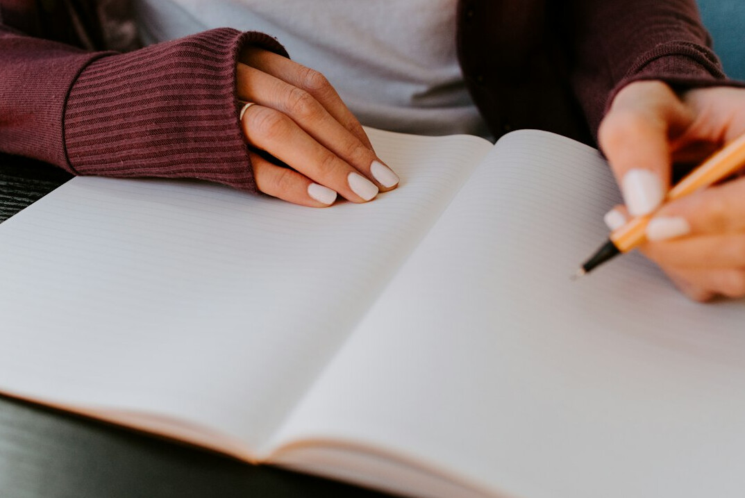 person writing in journal reflection